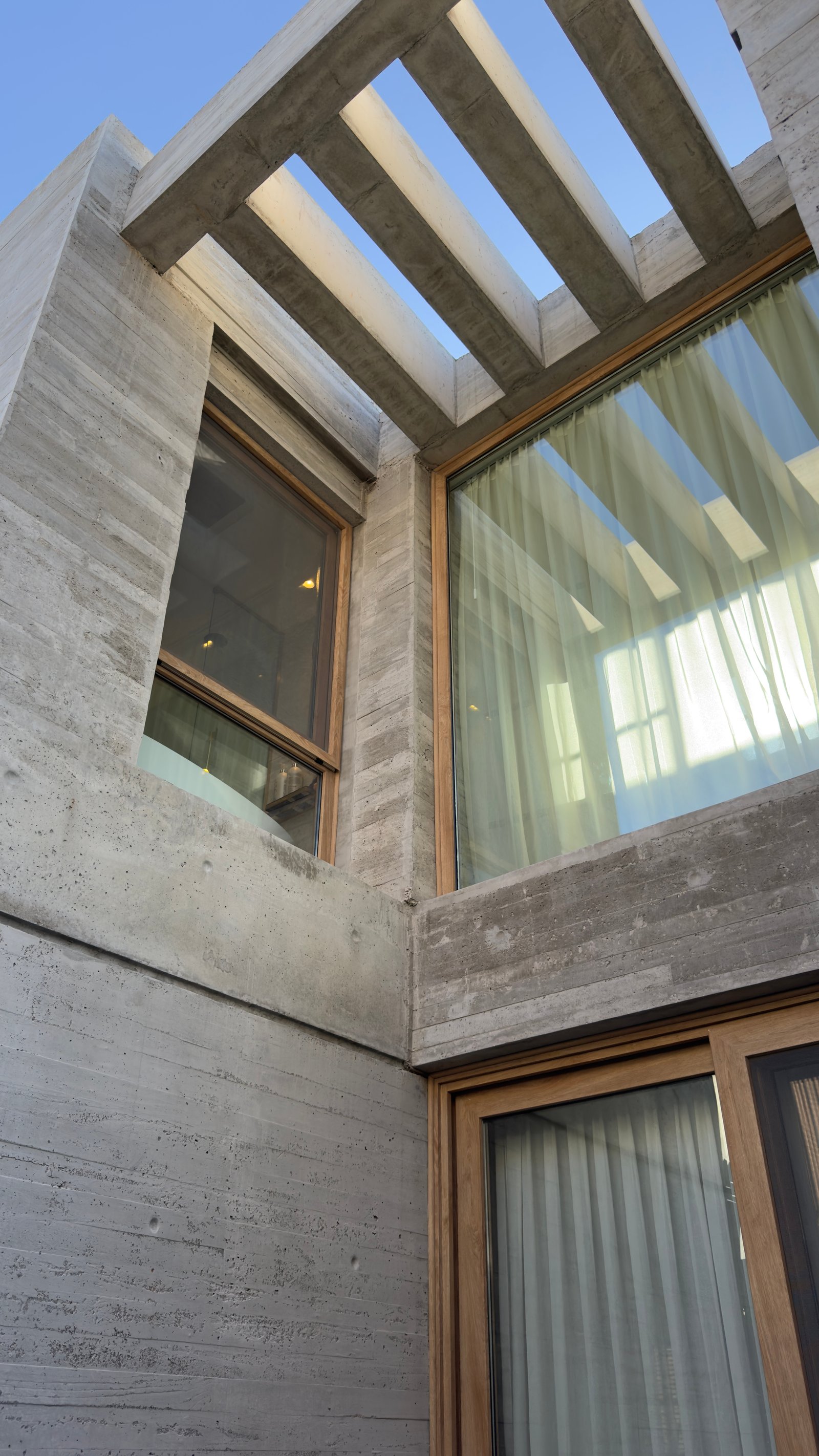 Fachada moderna de hormigón con pérgola y grandes ventanales — proyecto CASA MHN, por Hermann Arquitectos, en Nordelta